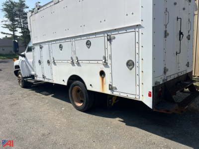 Utility service truck side view showing compartment doors on white GMC TopKick C4500 utility body with storage boxes along the side.