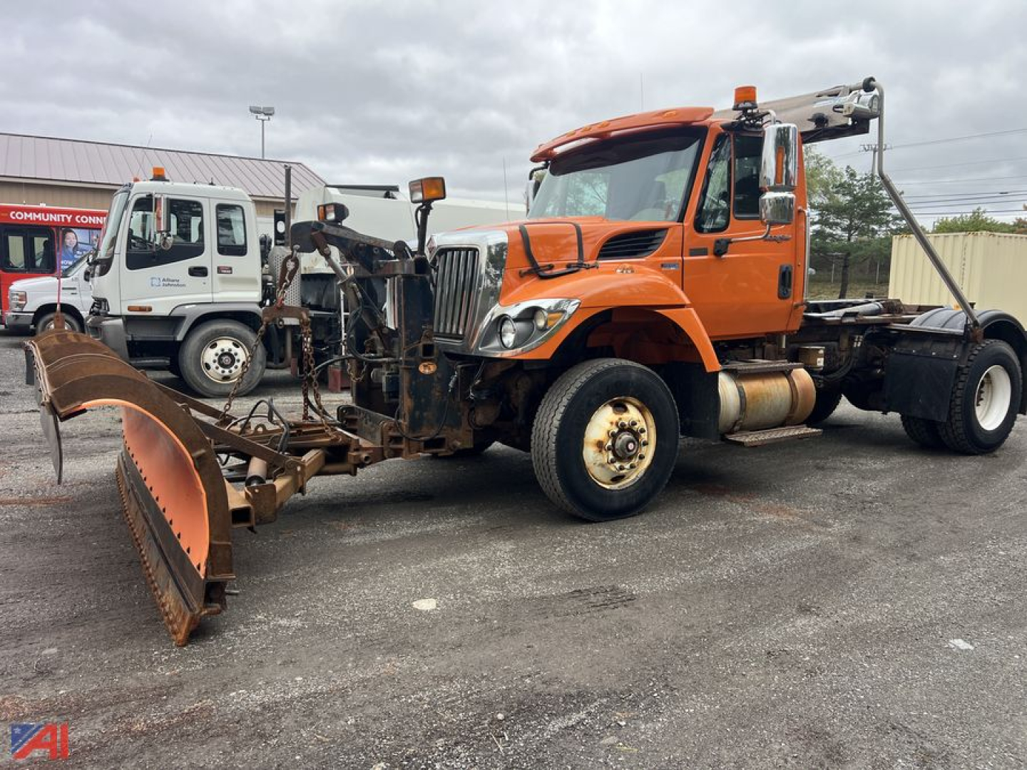 Truck with snow plow and hoist in front, orange International SA525 WorkStar 7400, side view showing plow, front grille, and wheel rims.