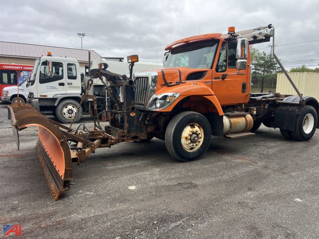 Truck with snow plow and hoist in front, orange International SA525 WorkStar 7400, side view showing plow, front grille, and wheel rims.