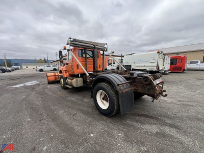 Orange International WorkStar roll-off cab with towing hitch and dual rear wheels, equipment frame, and exposed components.