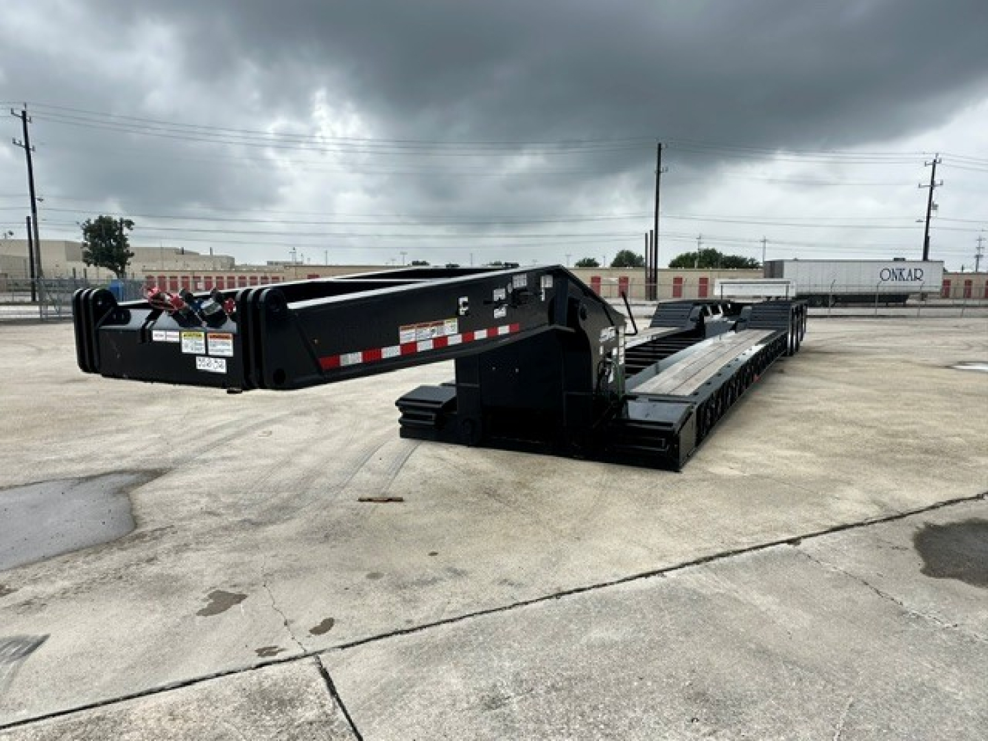 Load King trailer in parking lot showing lowboy deck and extendable gooseneck with black paint and reflective striping.