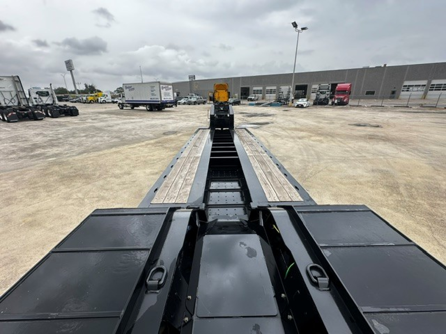 Trailer bed of a Load King lowboy showing dual steel deck sections and central tandem area under bright overcast sky.