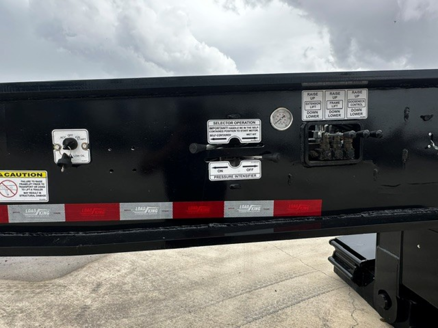 Trailer side panel showing multiple control labels and switches with caution stickers and reflective tape.