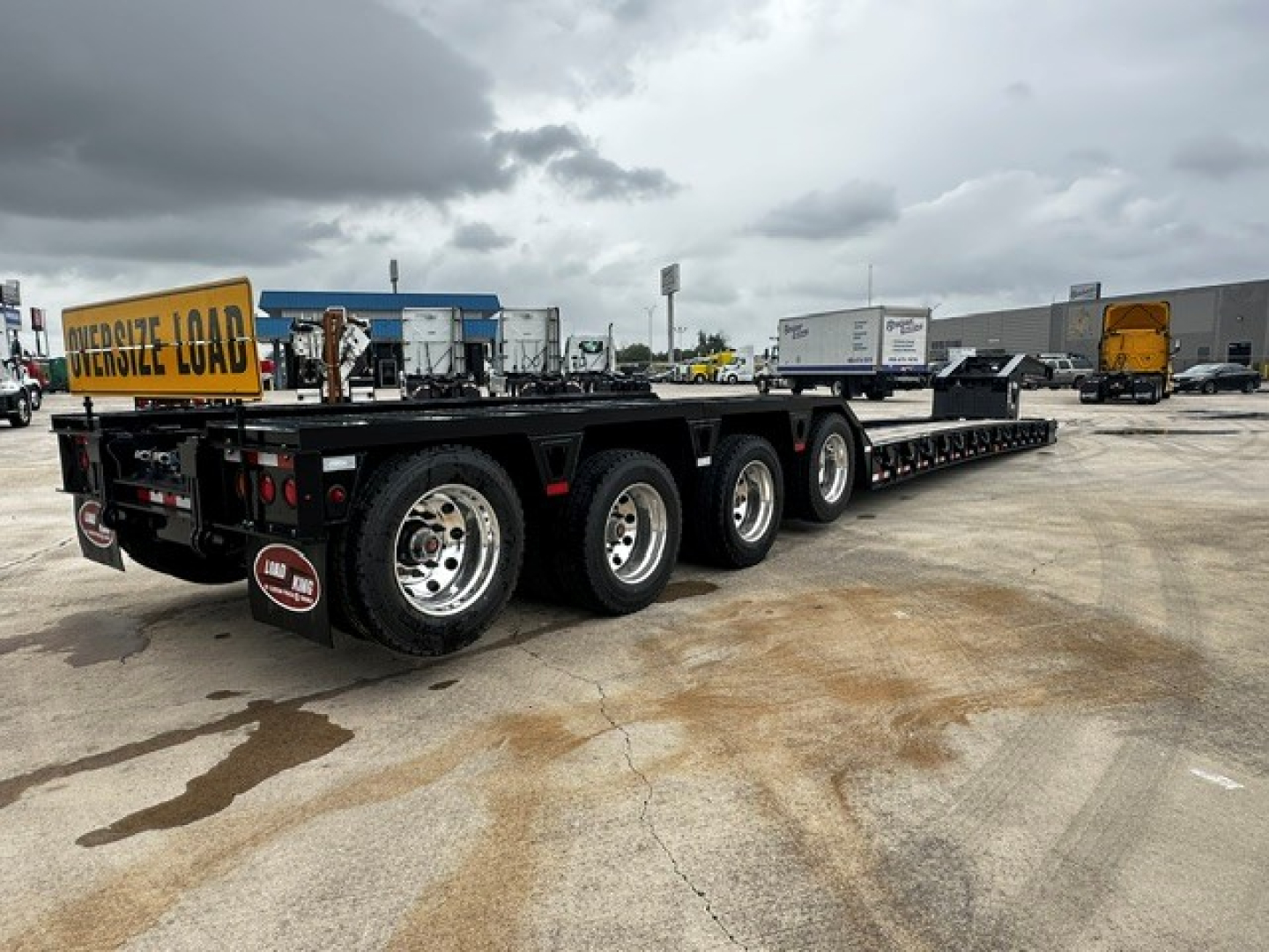 Trailer showing Load King heavy-duty lowboy with multiple axles and signage reading 'OVERSIZE LOAD' at rear. Visible text includes 'Load King' on side, '747' may be seen on plate.
