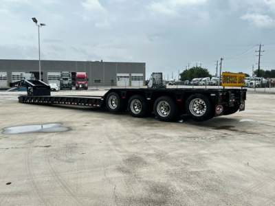 Heavy-duty lowboy trailer with triple axle, Load King logo and oversized load sign at rear; long flatbed with gooseneck hitch visible.