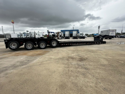 Load King lowboy trailer with multiple axles and equipment deck, side view showing long flatbed and mechanisms.