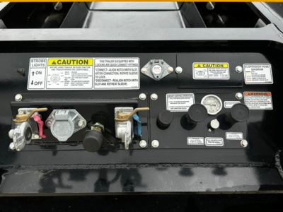 Trailer control panel with warning labels, gauges, and hydraulic levers on a Load King trailer.