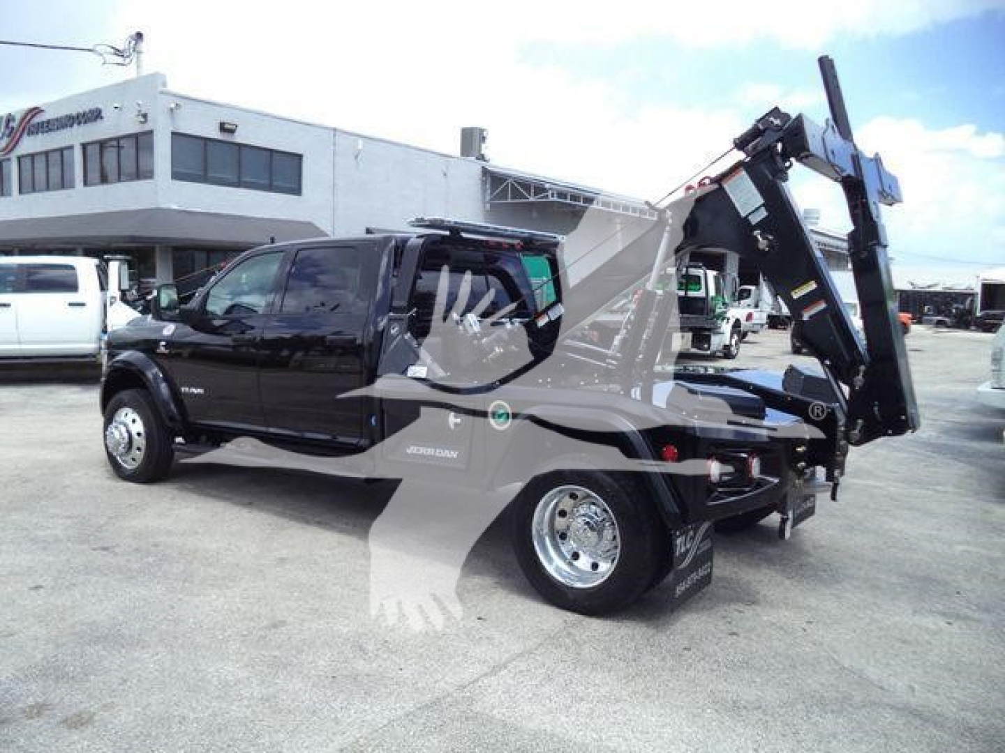 Ram 5500 tow truck with a hydraulic bed and crane, side view showing wheel, cab, and cargo bed.
