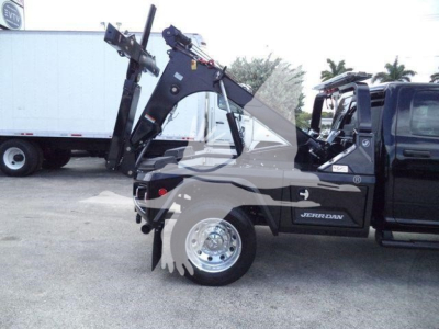 Ram 5500 Big Horn single cab truck with winch and crane arms, front-right view, black body, JERR-DAN branding, VIN and stock info not visible on label.