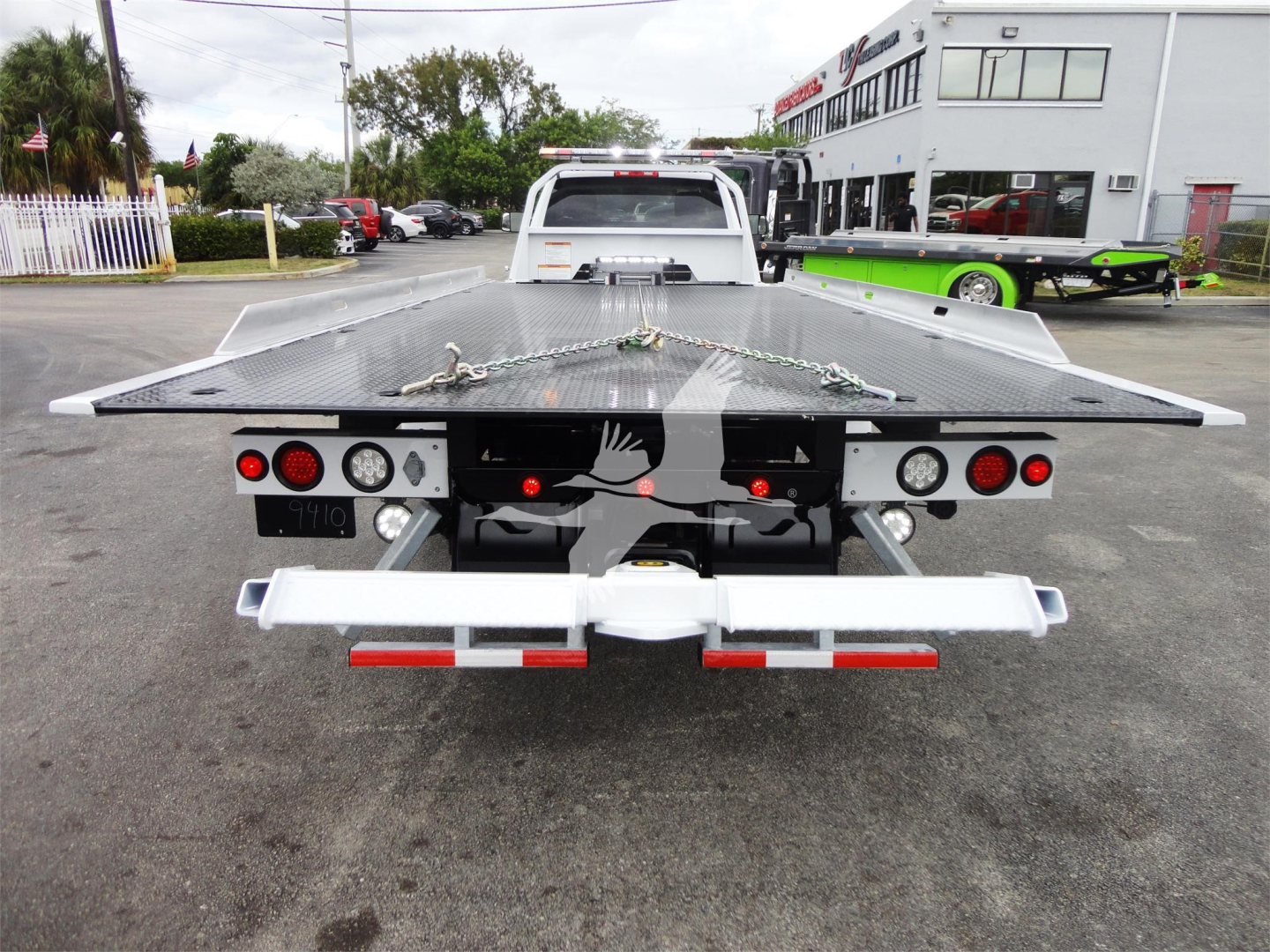 Flatbed tow truck bed on a 2023 Ram 5500 HD SLT showing rear platform with reflectors and lights.