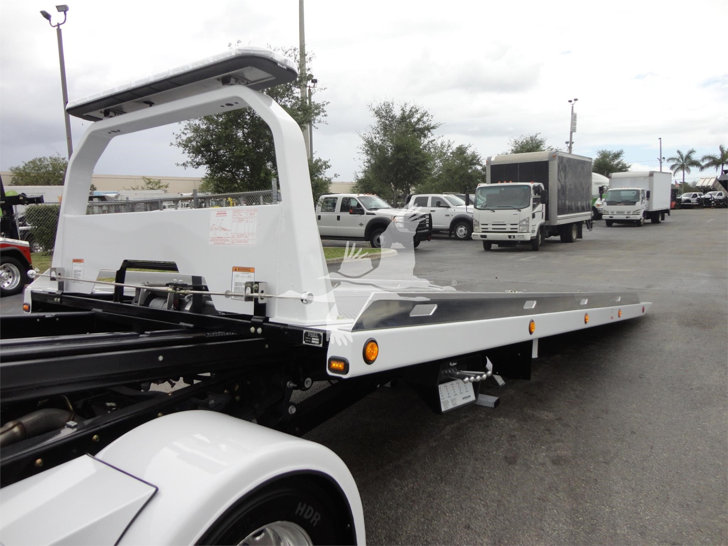 Flatbed rollback truck with Ram 5500 chassis showing long steel deck and rear winch area.