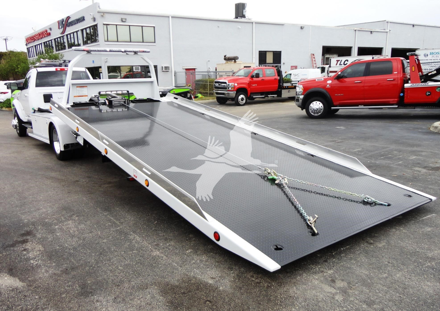 Ram 5500 rollback tow truck flatbed in service bay showing heavy-duty steel deck and winch with chains