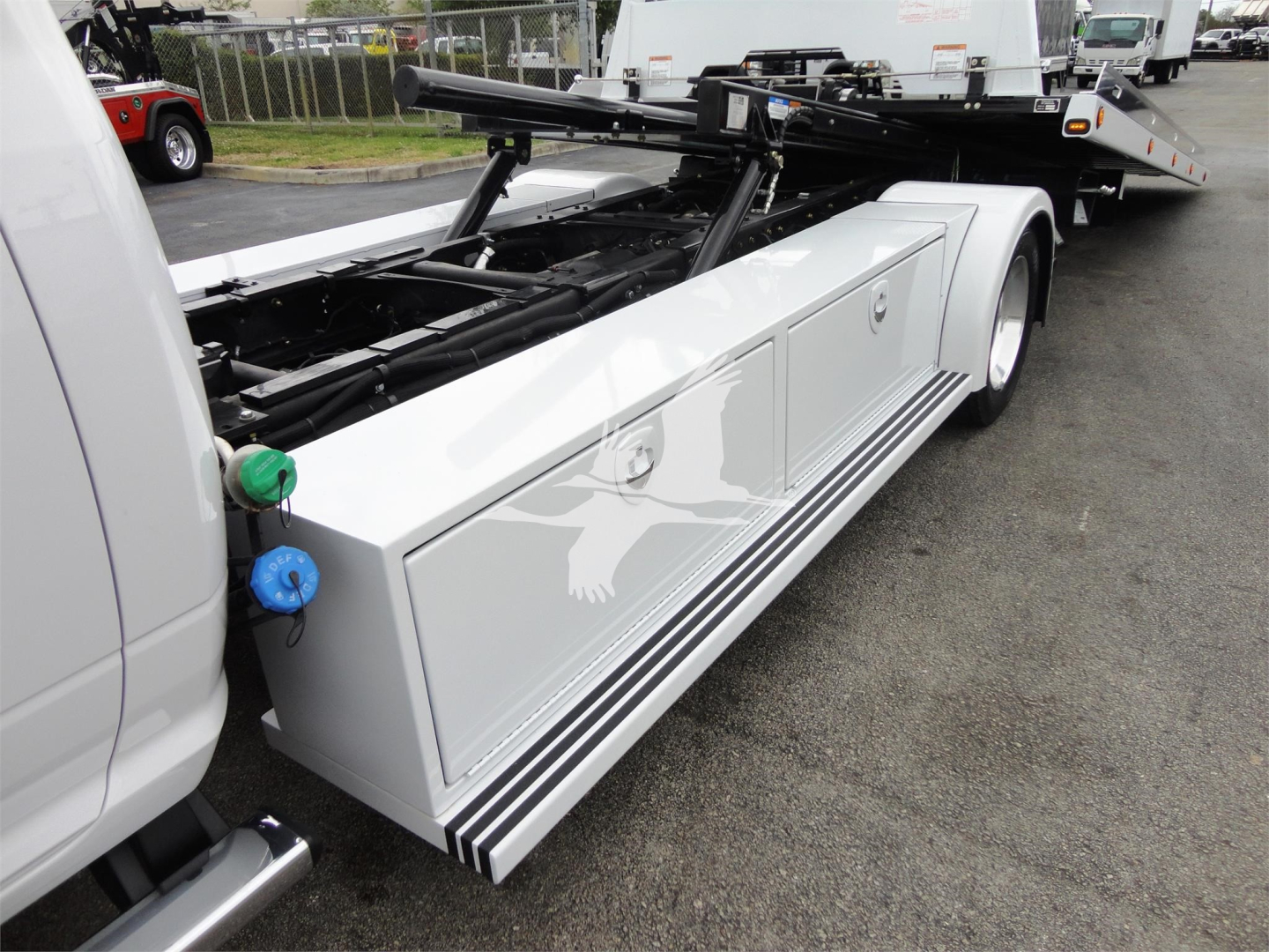 Ram 5500 rollback truck side view showing storage compartments and tow equipment with green and blue knobs.