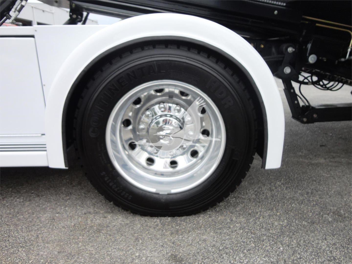 Wheel and fender of a white Ram 5500 rollback truck with a chrome wheel and Goodyear tire, partial side view.