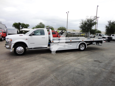 Ram 5500 heavy-duty rollback tow truck in white with flatbed, side view showing extended bed and wheel-lift equipment.