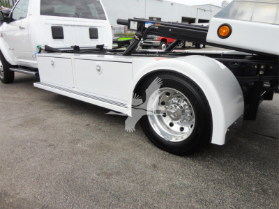 Ram 5500 Rollback utility truck side view showing white service body with storage drawers and large chrome wheel.