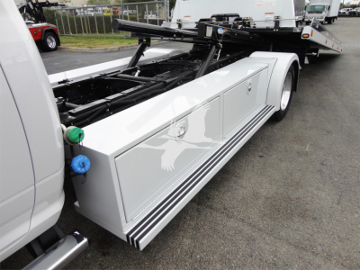Ram 5500 rollback truck side view showing storage compartments and tow equipment with green and blue knobs.