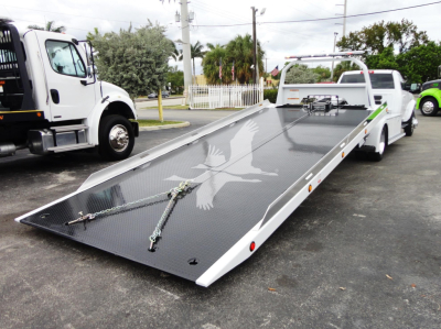 Ram 5500 rollback truck with flatbed, side rails, and dove graphic on metal platform.