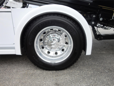 Wheel and fender of a white Ram 5500 rollback truck with a chrome wheel and Goodyear tire, partial side view.