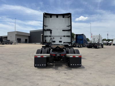 Volvo VNL64T860 tractor rear view showing bare fifth wheel, rear tires, and mud flaps with Volvo branding; spacious sleeper cab area and clear sky.