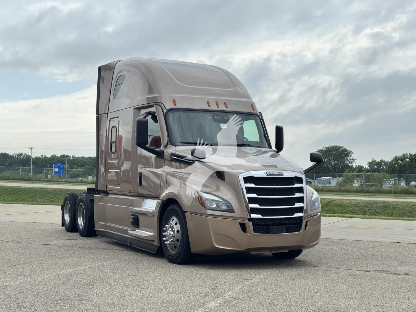 Truck front three-quarter view showing Freightliner Cascadia 126 sleeper cab with chrome grille and beige paint.