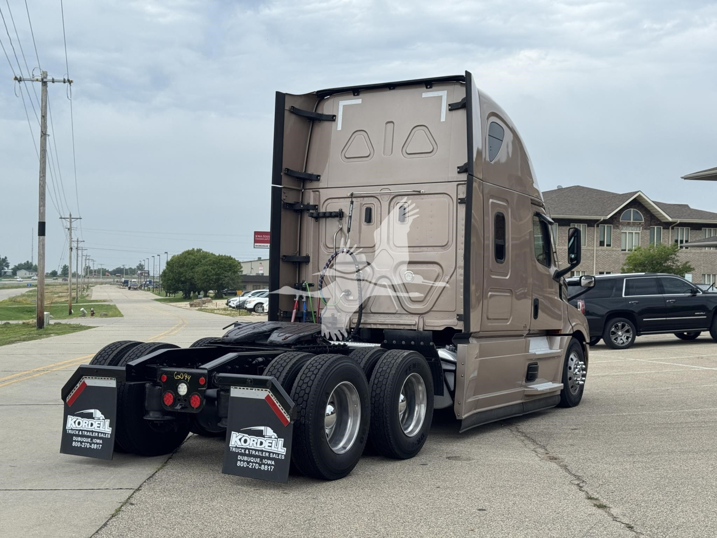 Truck rear view of a Freightliner Cascadia 126 sleeper tractor showing third axle and dual rear wheels with mud flaps and license plate area on a paved lot.