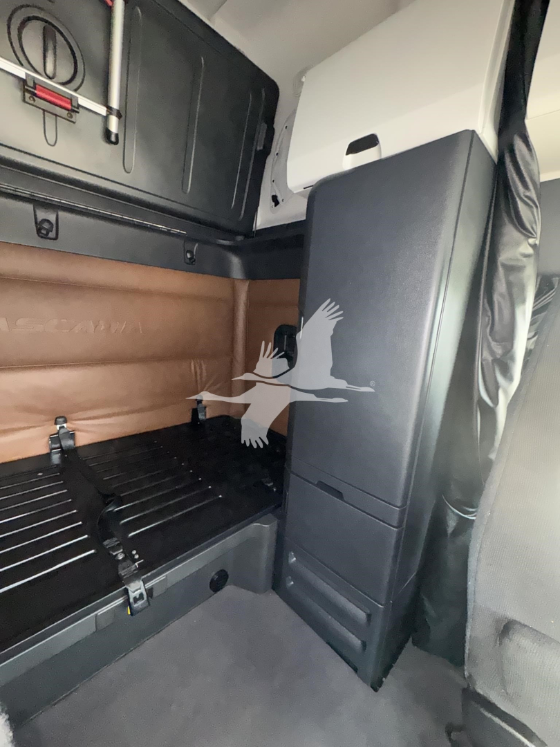 Freightliner Cascadia cab interior showing sleeper area with partition wall and storage cabinet.
