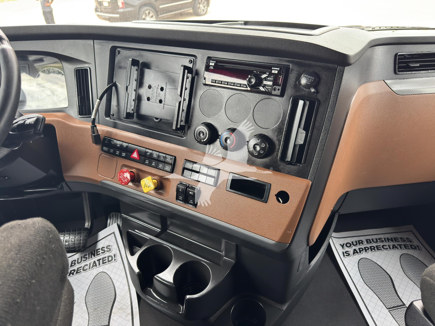 Cab interior of a Freightliner Cascadia dash showing empty dashboard panel, climate controls, cup holders, and radio slot.