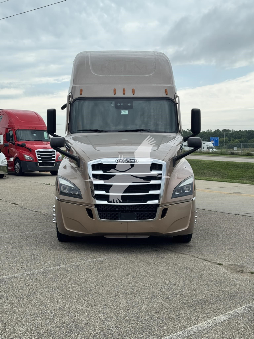 Front view of a Freightliner Cascadia sleeper cab truck with a chrome grille and beige paint, badge on hood, headlights, and side mirrors visible.