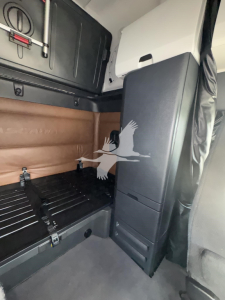 Freightliner Cascadia cab interior showing sleeper area with partition wall and storage cabinet.