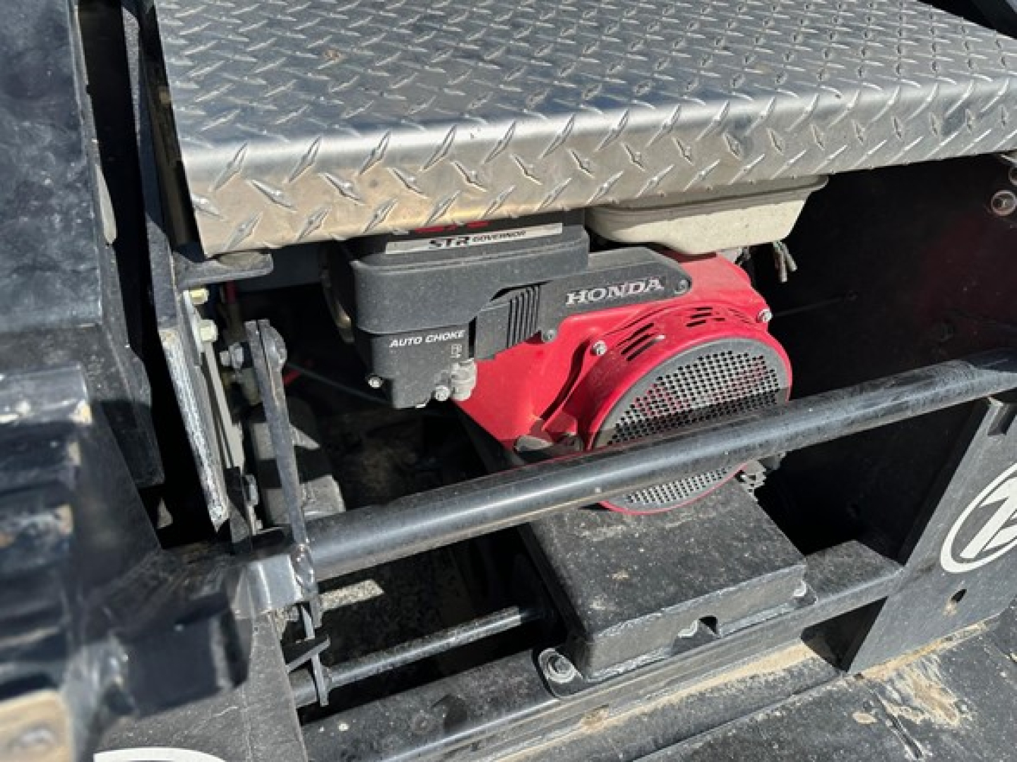 Trailer showing Honda engine with red recoil start, diamond plate toolbox and metal steps.