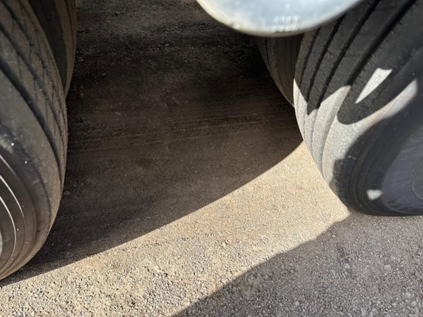 Trail-Eze TE110DG trailer wheel area showing dual tires and shadowed ground between tires.