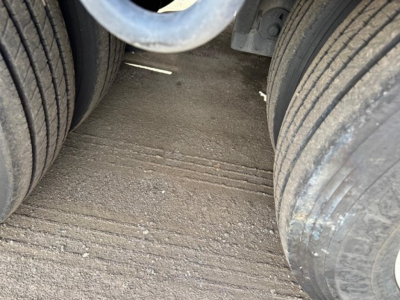 Te110dg Trail-Eze lowboy trailer wheel area with dual rear tires and dirt surface between wheels.
