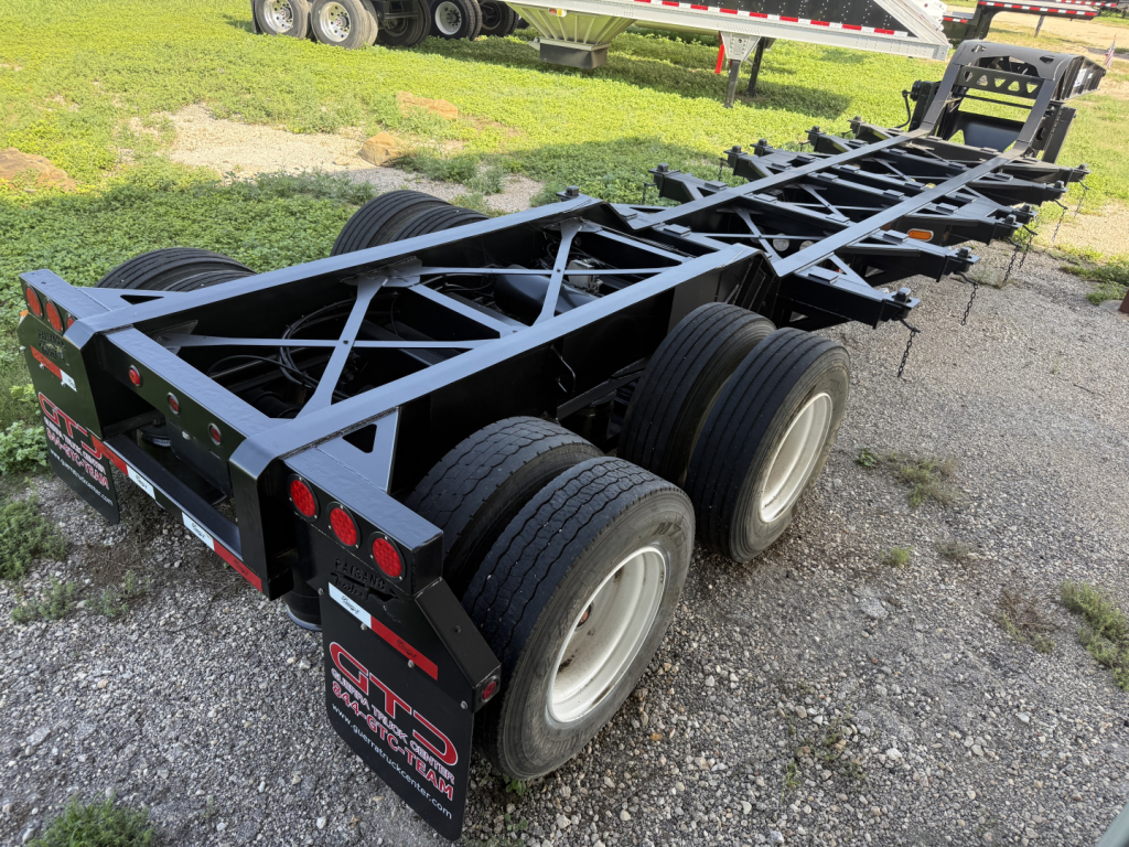 Chassis/frame of a trailer showing the rear with dual axle wheels and structural lattice, with GAP license and company stickers on the back.