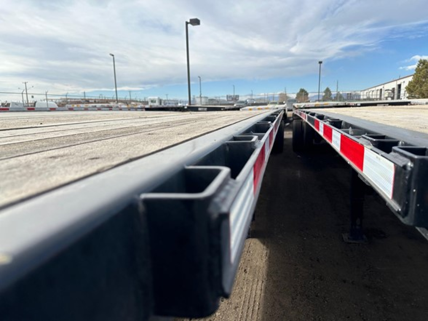 Trailer side view of a Wabash air ride flatbed showing steel frame, side rails, and red/white reflective safety markings.