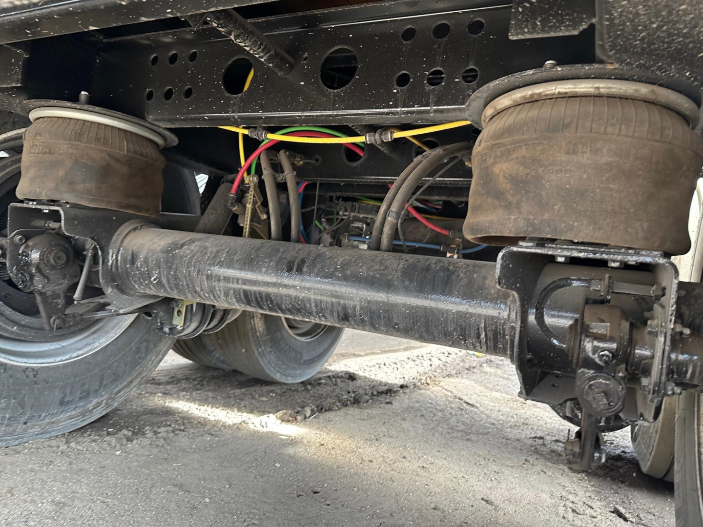 Trailer undercarriage showing air ride suspension with tandem axles, air springs, and driveshaft area; hoses and wiring visible.