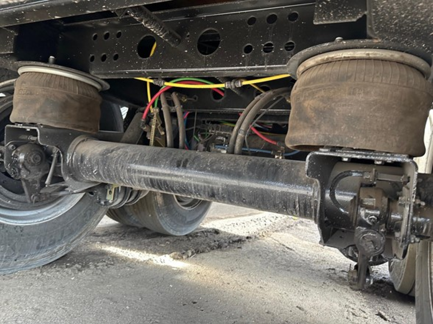 Trailer undercarriage of a used 2024 Wabash air ride steel flatbed showing axle with suspension beam and brake components.