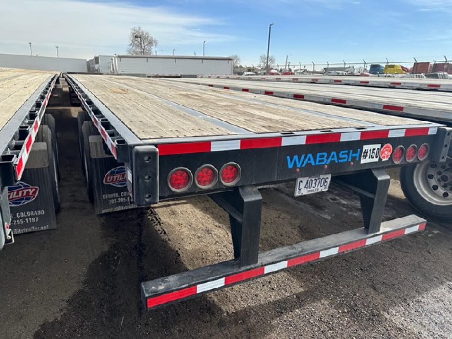 Flatbed trailer with Wabash logo showing air ride steel bed and rear bumper with lights and reflective tape.