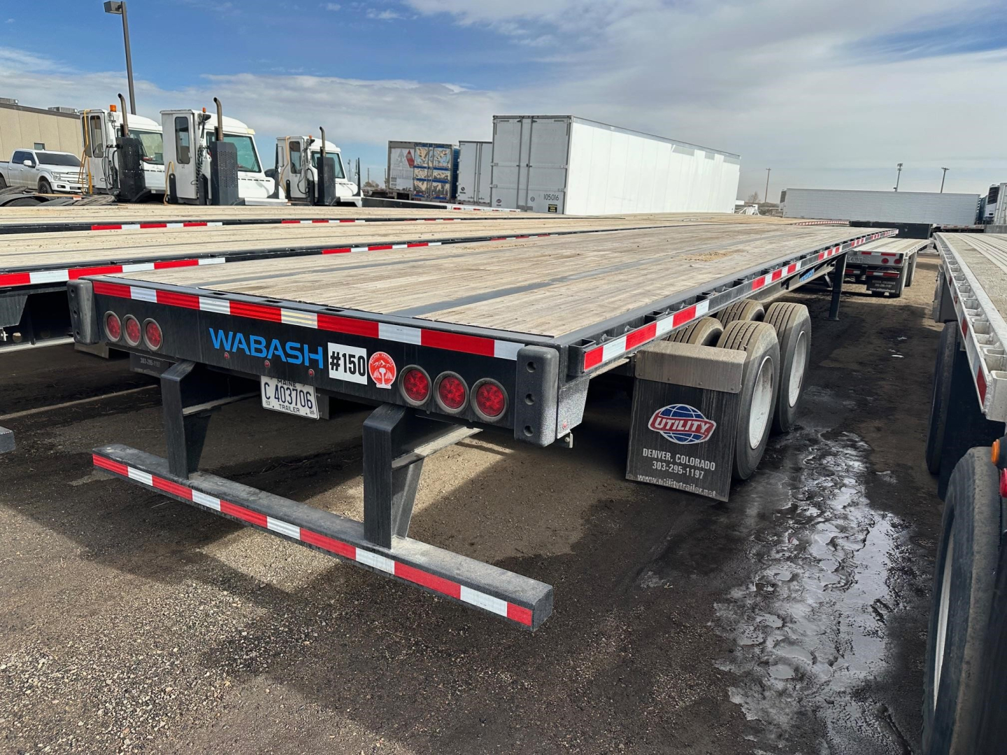 Wabash flatbed trailer rear showing air ride suspension and multiple round taillights with WABASH branding and stock numbers.