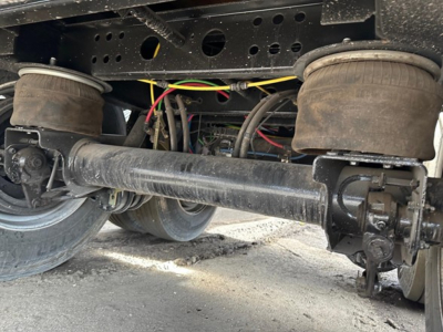 Trailer undercarriage of a used 2024 Wabash air ride steel flatbed showing axle with suspension beam and brake components.