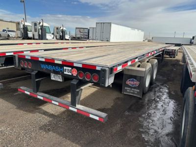 Flatbed trailer rear showing Wabash logo, 150 sticker, taillights, and reflective safety markings; wooden deck; mud flaps; dual rear axles.