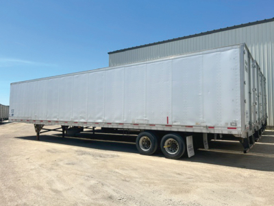Utility trailer showing a long silver rectangular cargo trailer with dual rear axles and a boxy front, side view.