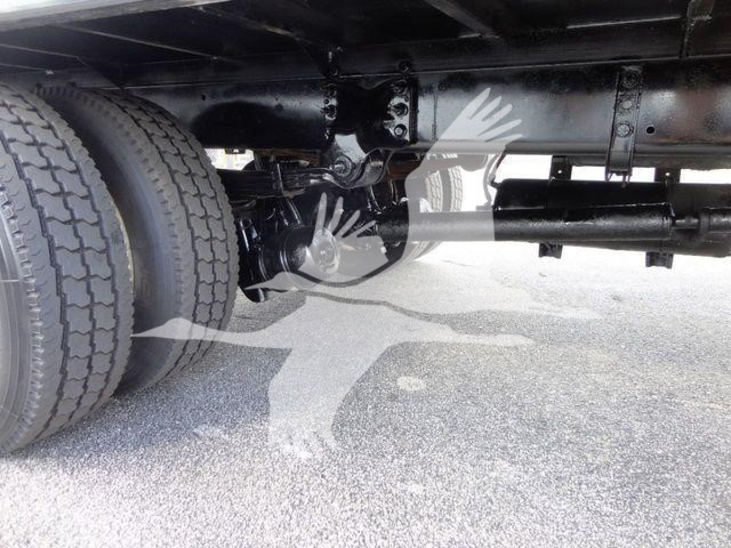 Underbody view of a Freightliner M2 106 truck showing dual rear wheels, driveshaft, suspension, and chassis components.