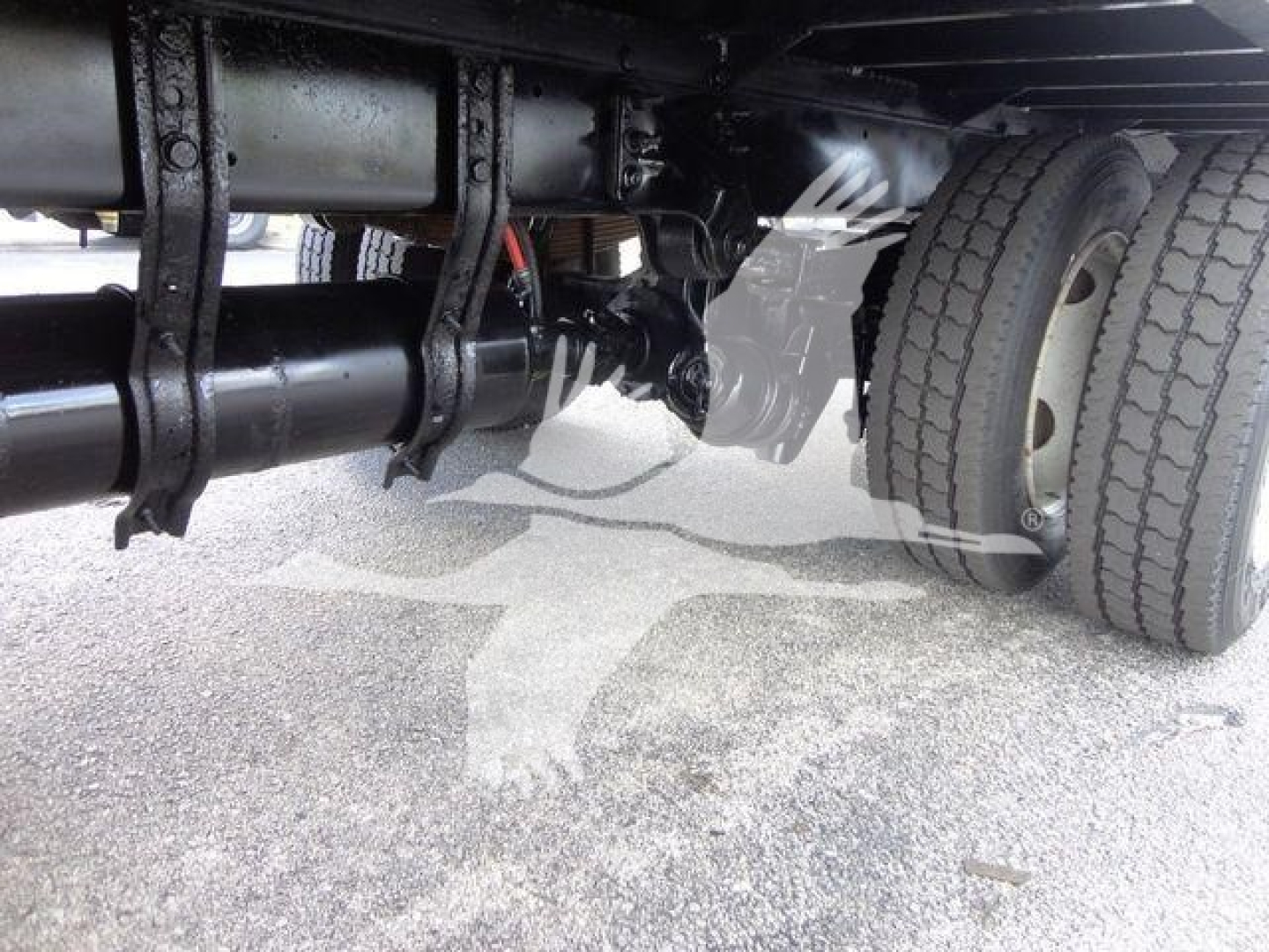 Freightliner M2 106 undercarriage showing suspension, driveshaft, and dual rear wheels; metal frame and underbody components visible