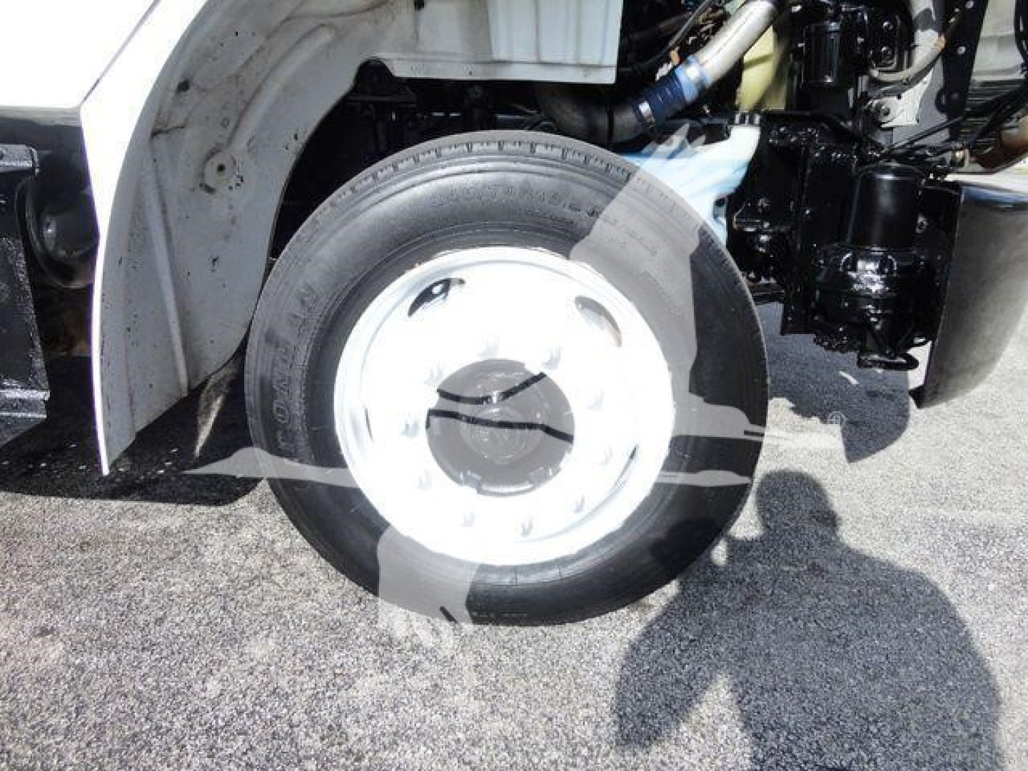Rear wheel and suspension of a Freightliner M2 106 flatbed truck showing front wheel with hub and part of chassis.