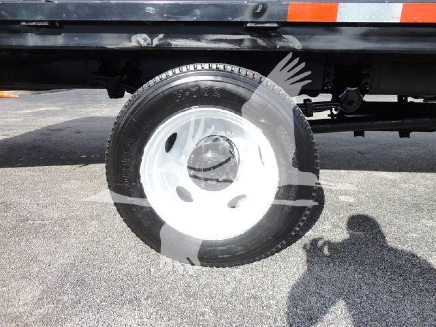 Wheel and part of flatbed truck showing steel wheel with white hubcap and tire on Freightliner M2 106.