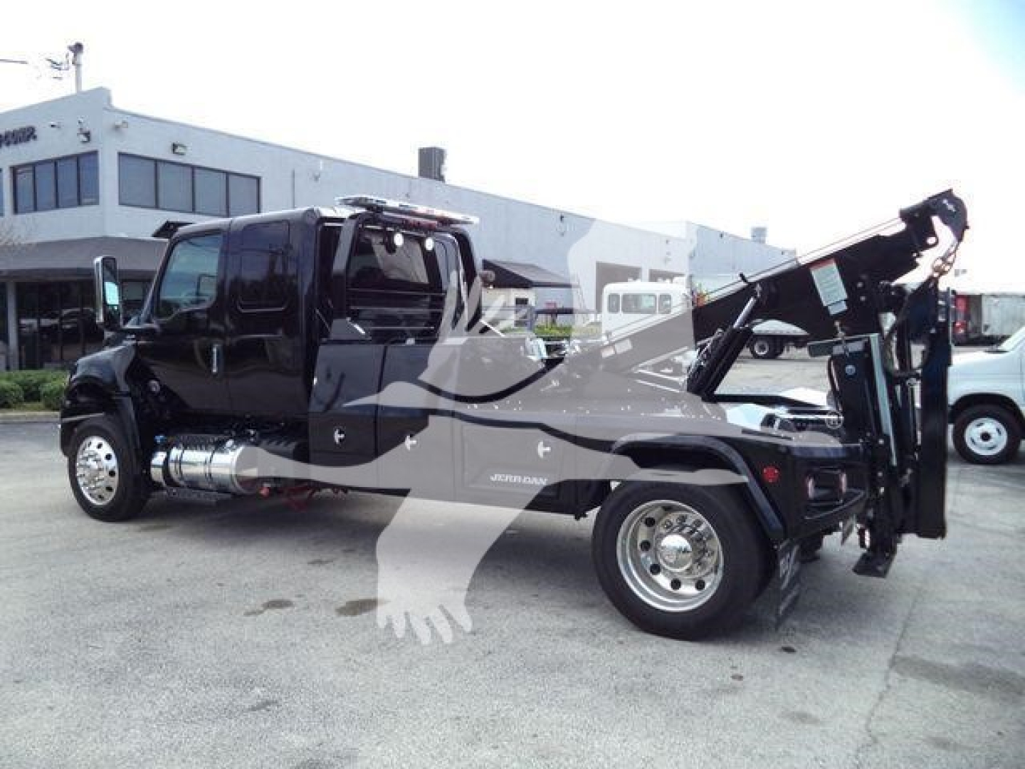 International MV tow truck with crane in service bed and chrome fuel tanks, side view showing dual rear wheels and winch arm.