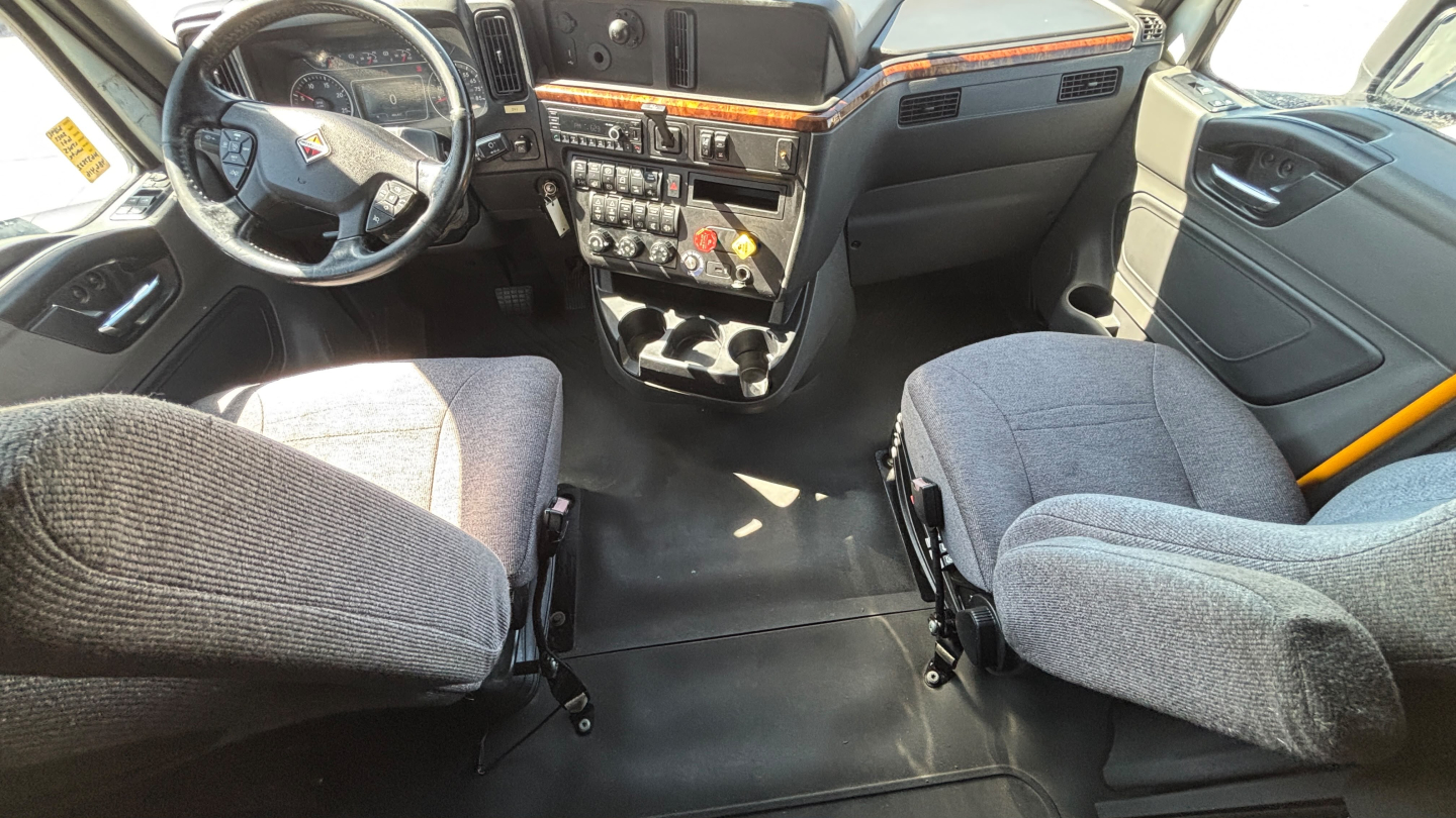 Cab interior of a 2022 International LT625 truck showing steering wheel, dashboard, center console, and two captain seats.