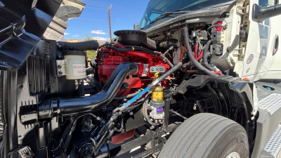International LT625 truck engine bay showing red engine block, black intercooler pipe, yellow oil filter, and exposed wiring