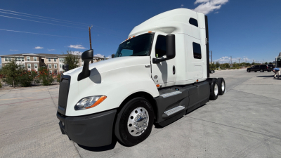 International LT625 truck cab and sleeper on a lot, side view showing white exterior and black bumper.